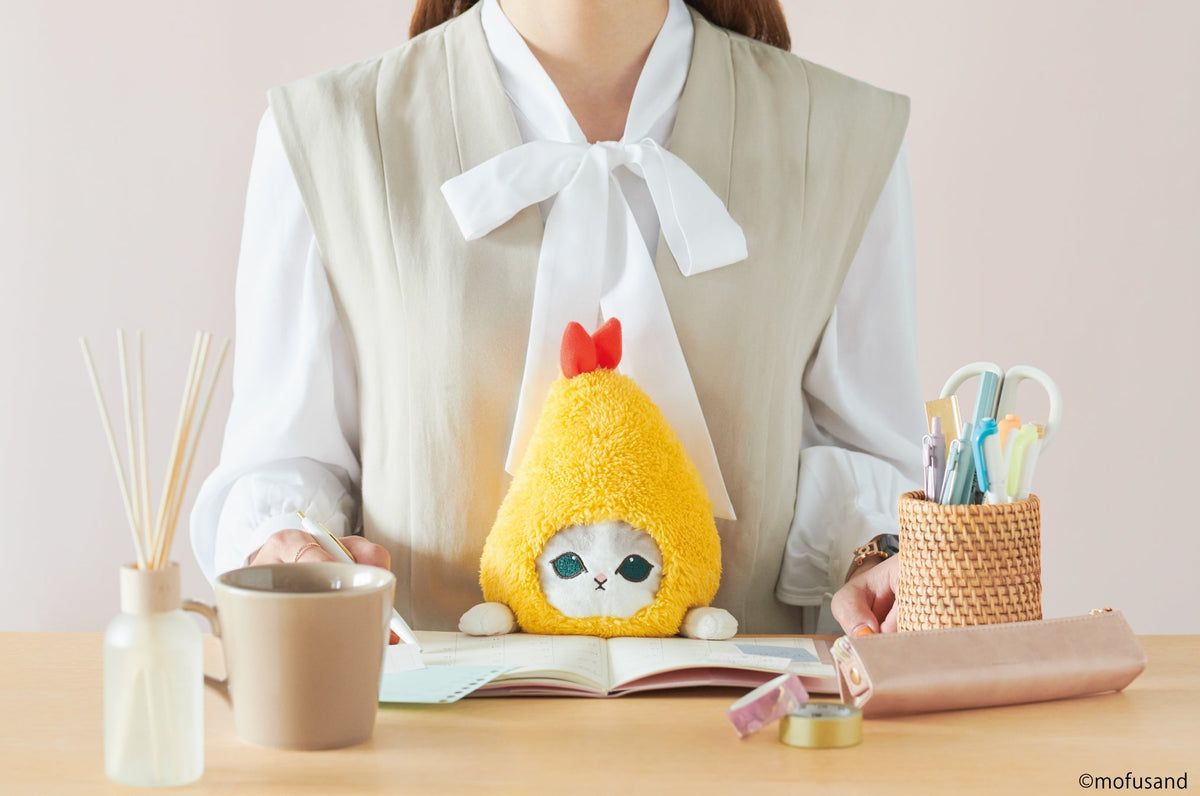 lifestyle image of posture pal mofusand shrimp meow. features a front facing view of person in a gray blouse writing in a planner using shrimp meow at desk